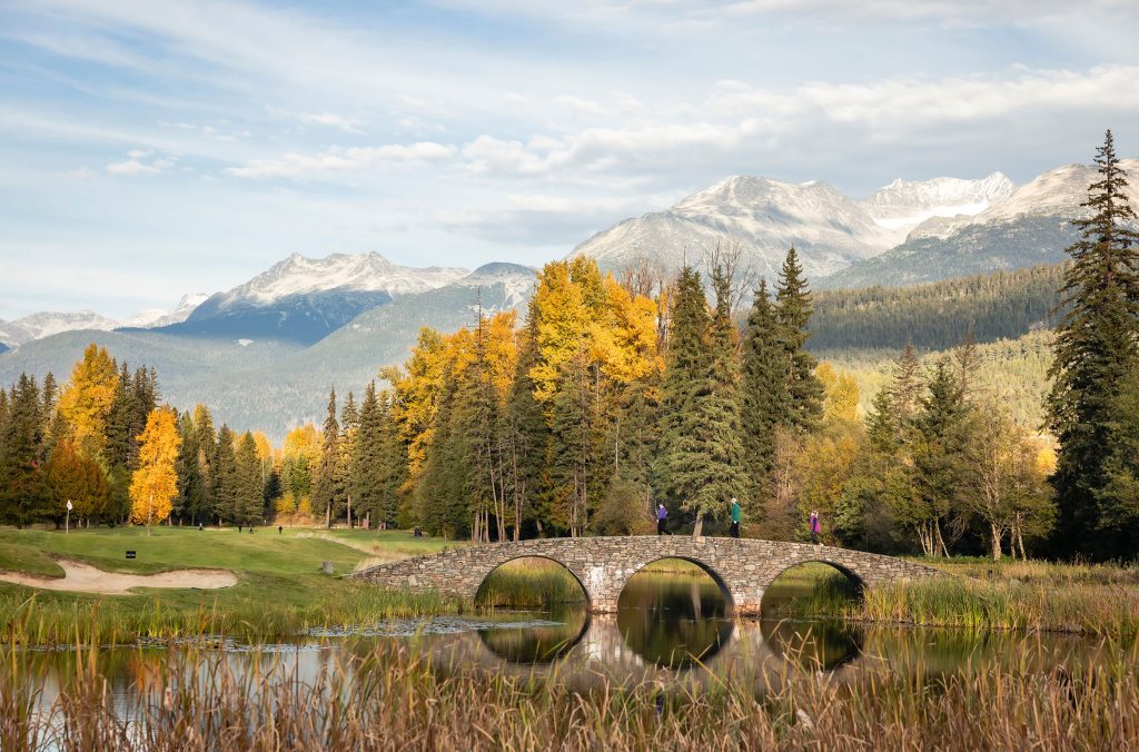 Golfers walk across a bridge amidst the fall colours at Nicklaus North Golf Course.