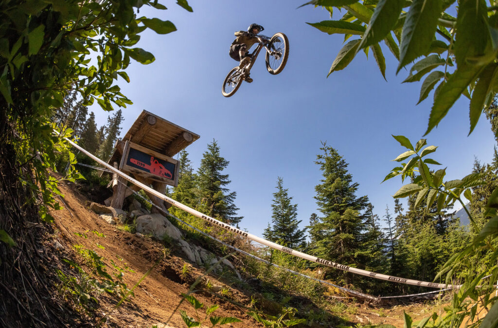 A biker soars through the air jumping off a feature on the 1199 trail during a Crankworx race in the Whistler Mountain Bike Park.