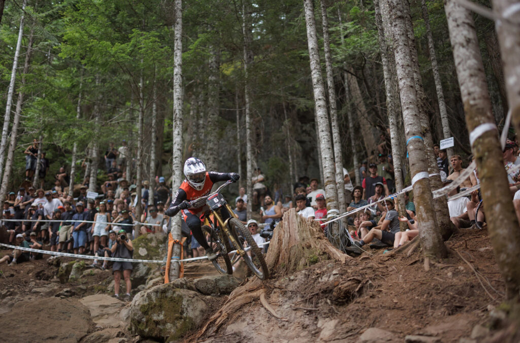 A bike rider races around a rocky and rooty corner on the 1199 trail in Whistler Mountain Bike Park during Crankworx.