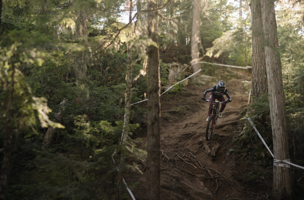 A bike rider races around a rocky and rooty corner on the 1199 trail in Whistler Mountain Bike Park during Crankworx.