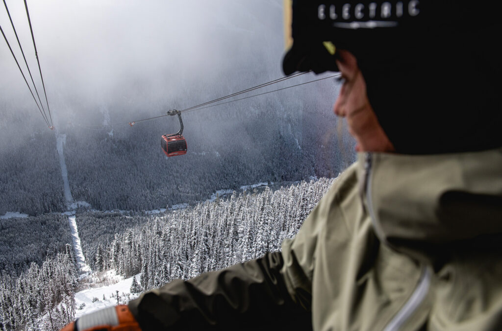 A person looks out over the valley between Whistler and Blackcomb mountain as they cross on the PEAK 2 PEAK Gondola in the winter.