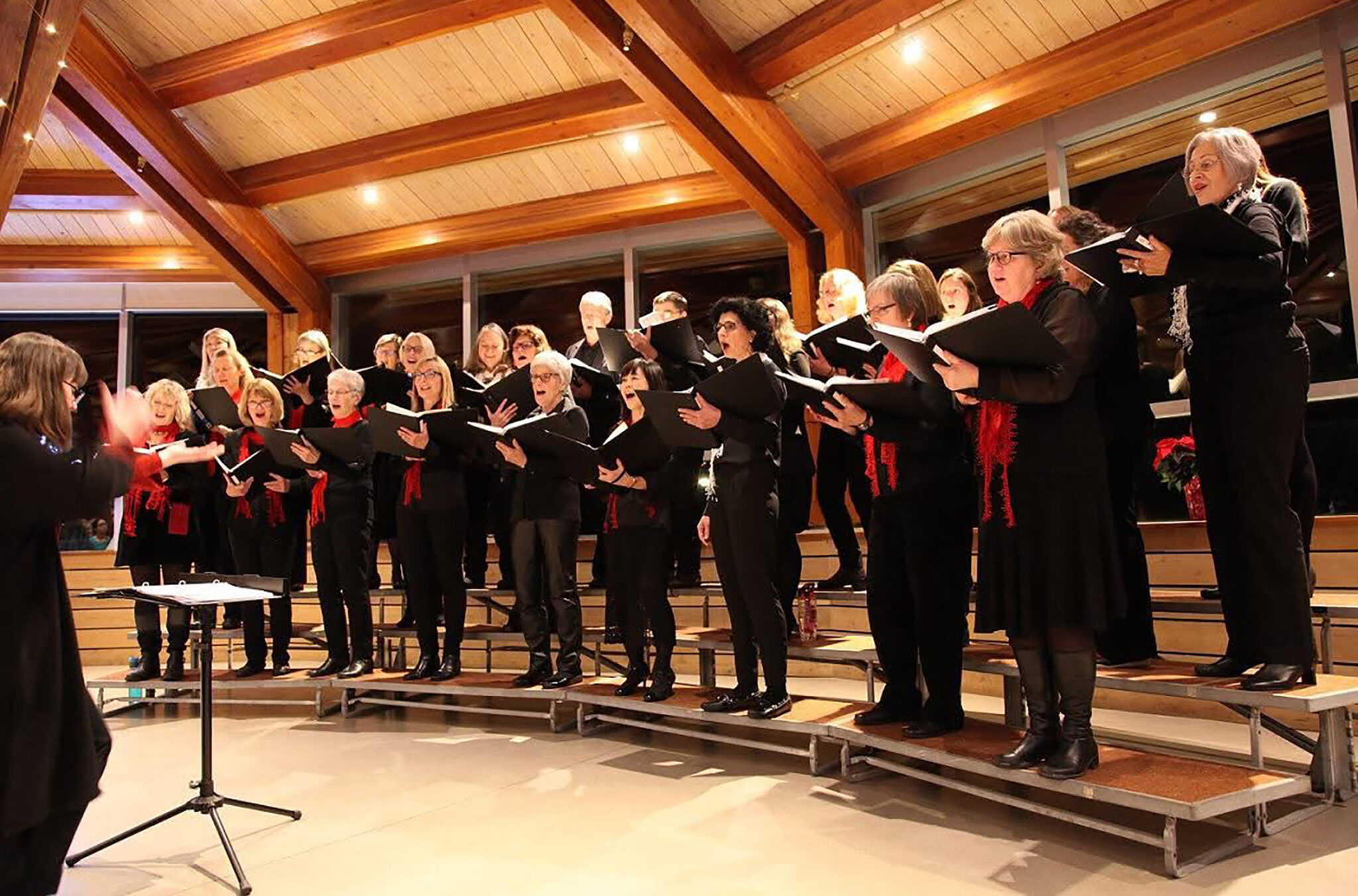 The Whistler Singers performing at the Squamish Lil'wat Cultural Centre in 2022. They are all dressed in black with red scarves. 