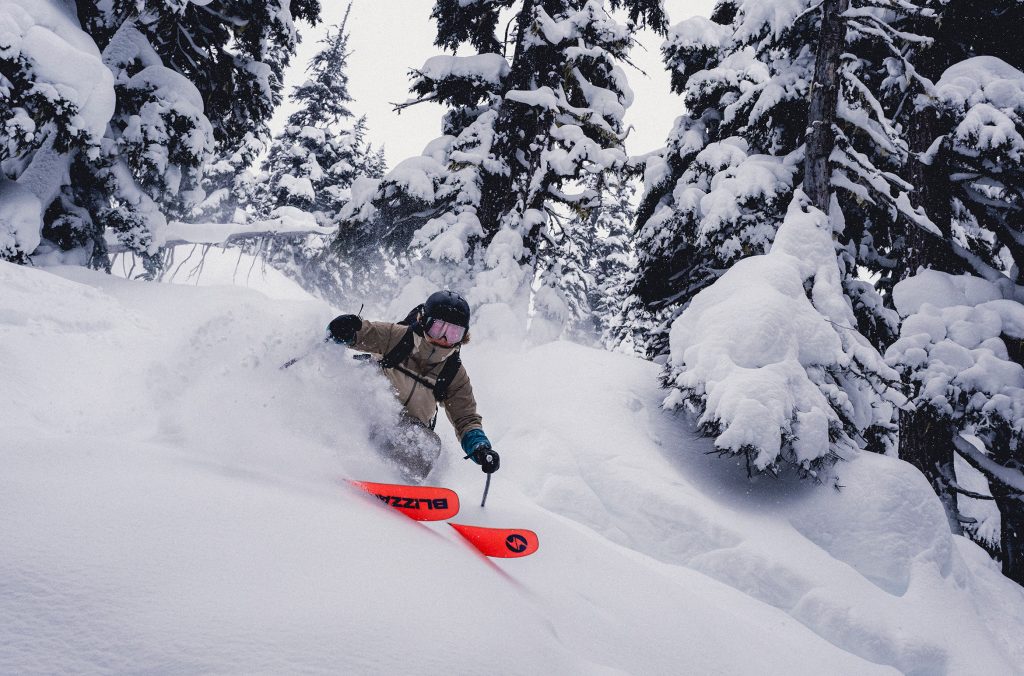 A skier charges through thick snow amongst the trees on Whistler Blackcomb.