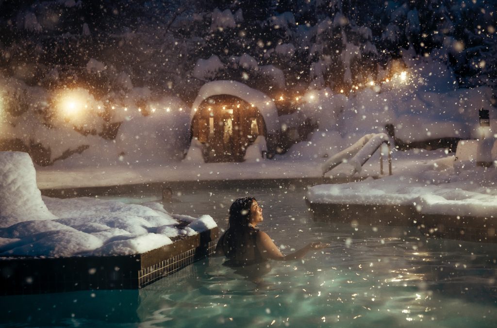 A person enjoys the pool at the Four Seasons Hotel Whistler as the snow falls.