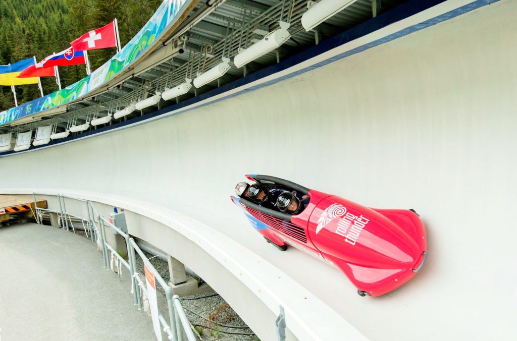 Three people head down the bobsleigh track in Rolling Thunder, Whistler's summer bobsleigh experience.