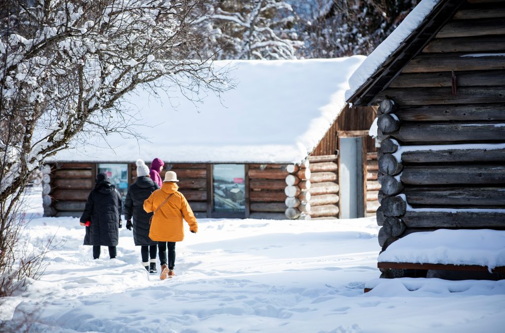 A group of sightseers with Whistler Valley Tours explore the cabins at Rainbow Lake in winter.