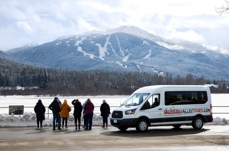 A group of sightseers enjoy a tour with Whistler Valley Tours as they stop at Green Lake in the winter.