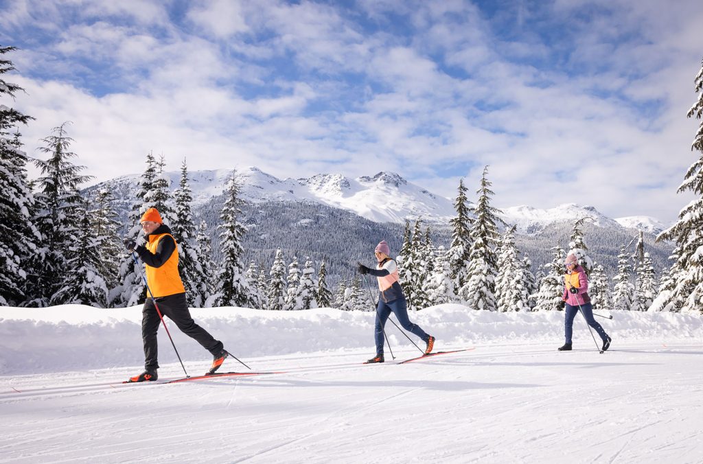 Three skiers enjoy the cross-country trails at Whistler Olympic Park in the winter sunshine. 