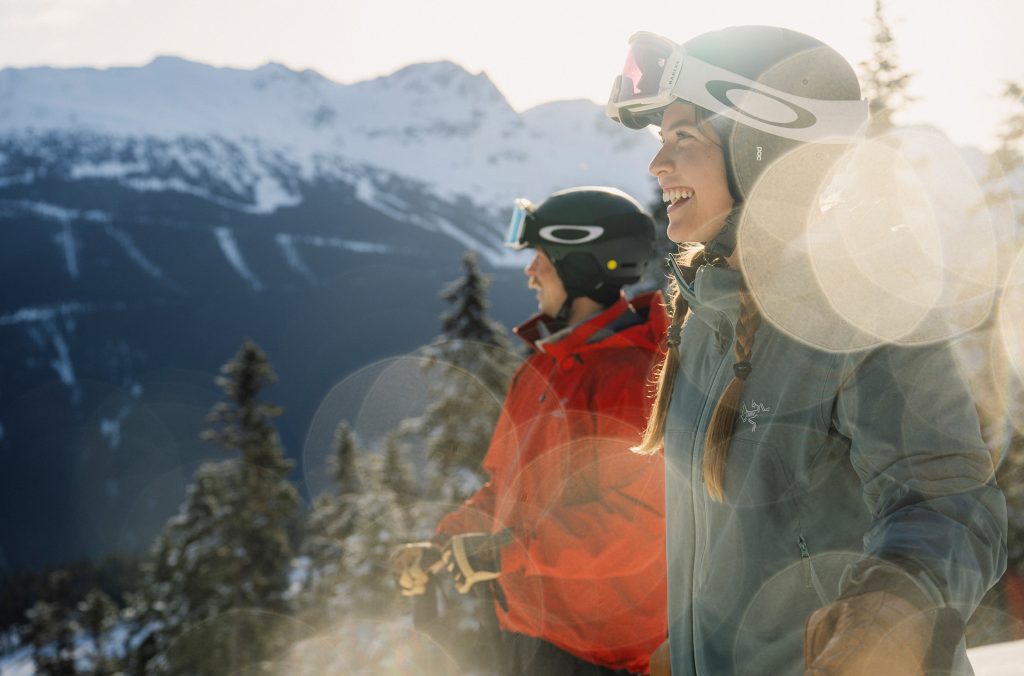 Two skiers look out across Whistler Blackcomb in the spring sunshine.