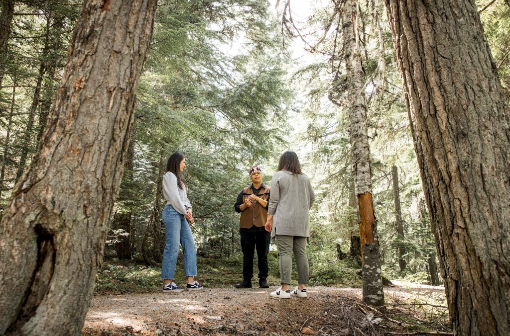 An ambassador from the Squamish Lil'wat Cultural Centre takes two people on a guided walk in the forest.
