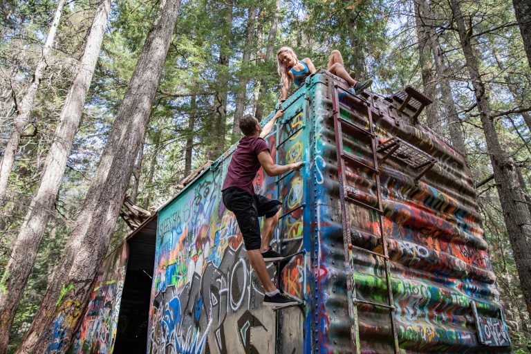 Two people explore the abandoned train cars on the Train Wreck hike in Whistler.