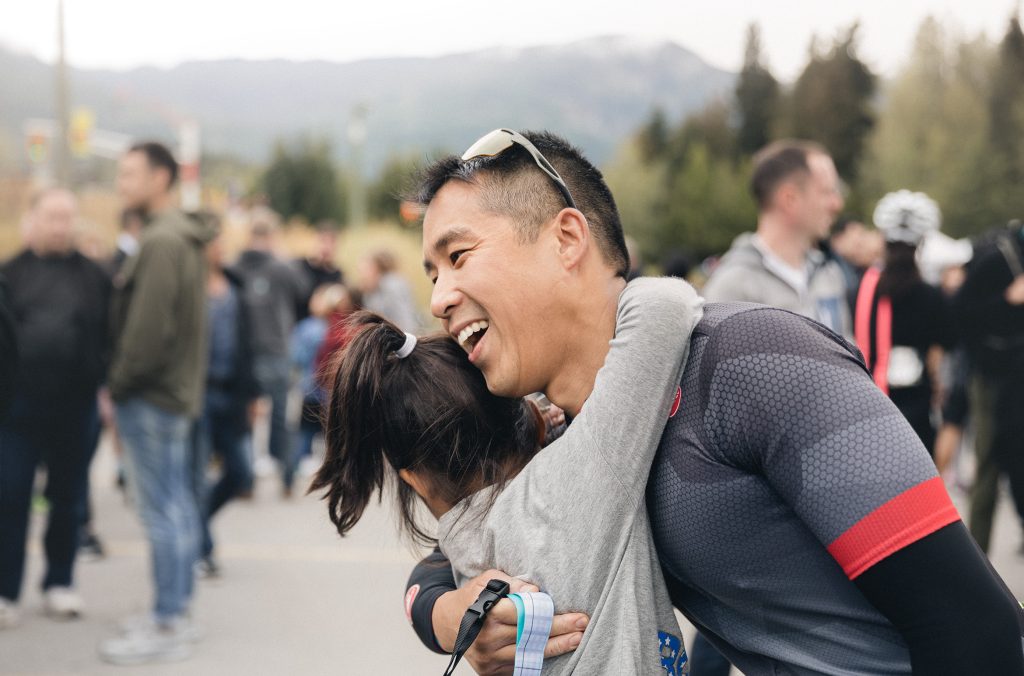Two people hug after one of them completes the cycle from Vancouver to Whistler, part of GranFondo Whistler.