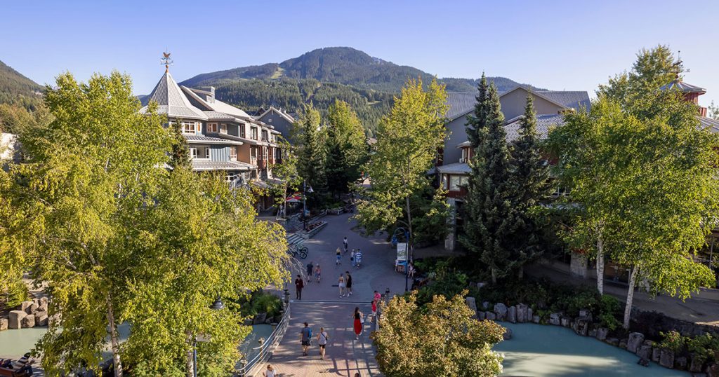 Whistler Village in the summer time with the mountains as the backdrop.