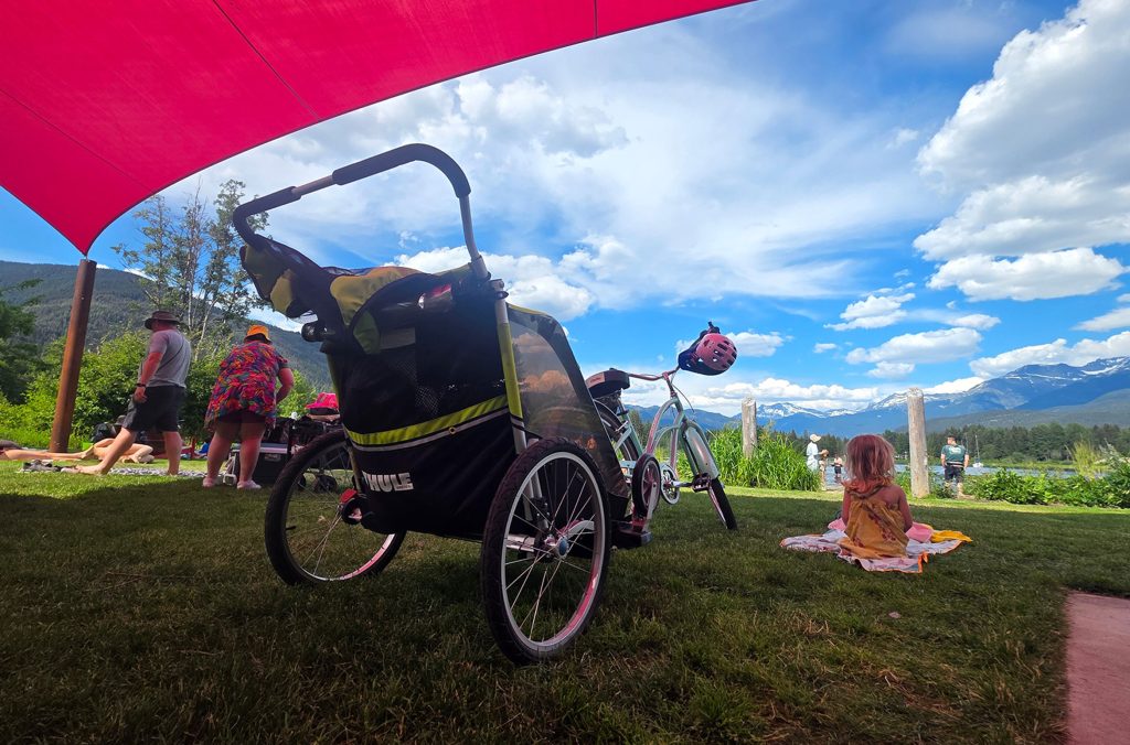 A bike chariot is parked under the shade at Rainbow Park in Whistler.