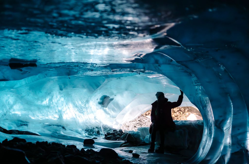 A person touches the sculpted walls of an ice cave in Whistler on a tour with Beyond Whistler.