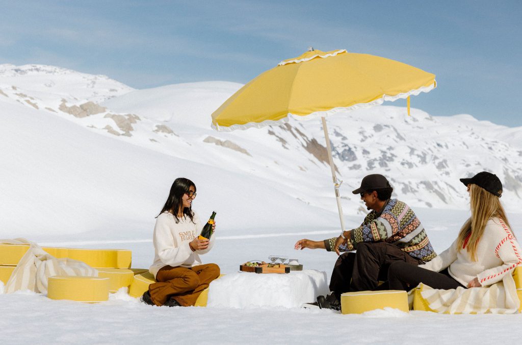 Three people enjoy apres on a glacier after exploring the ice caves with Beyond Whistler.