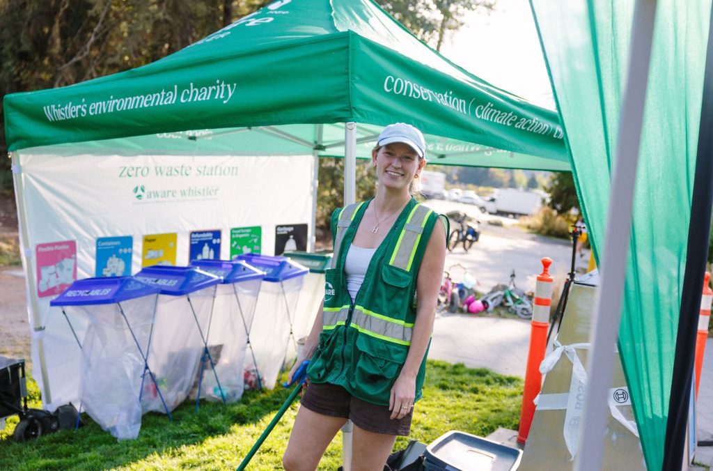 A Zero Waste Heroes volunteer stands under their trash tent at a Whistler skate jam event.