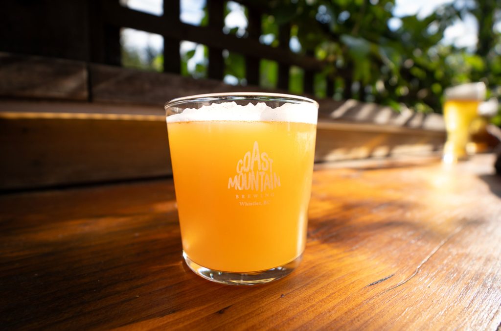 A glass of beer sits in the sunshine at Coast Mountain Brewing in Whistler.