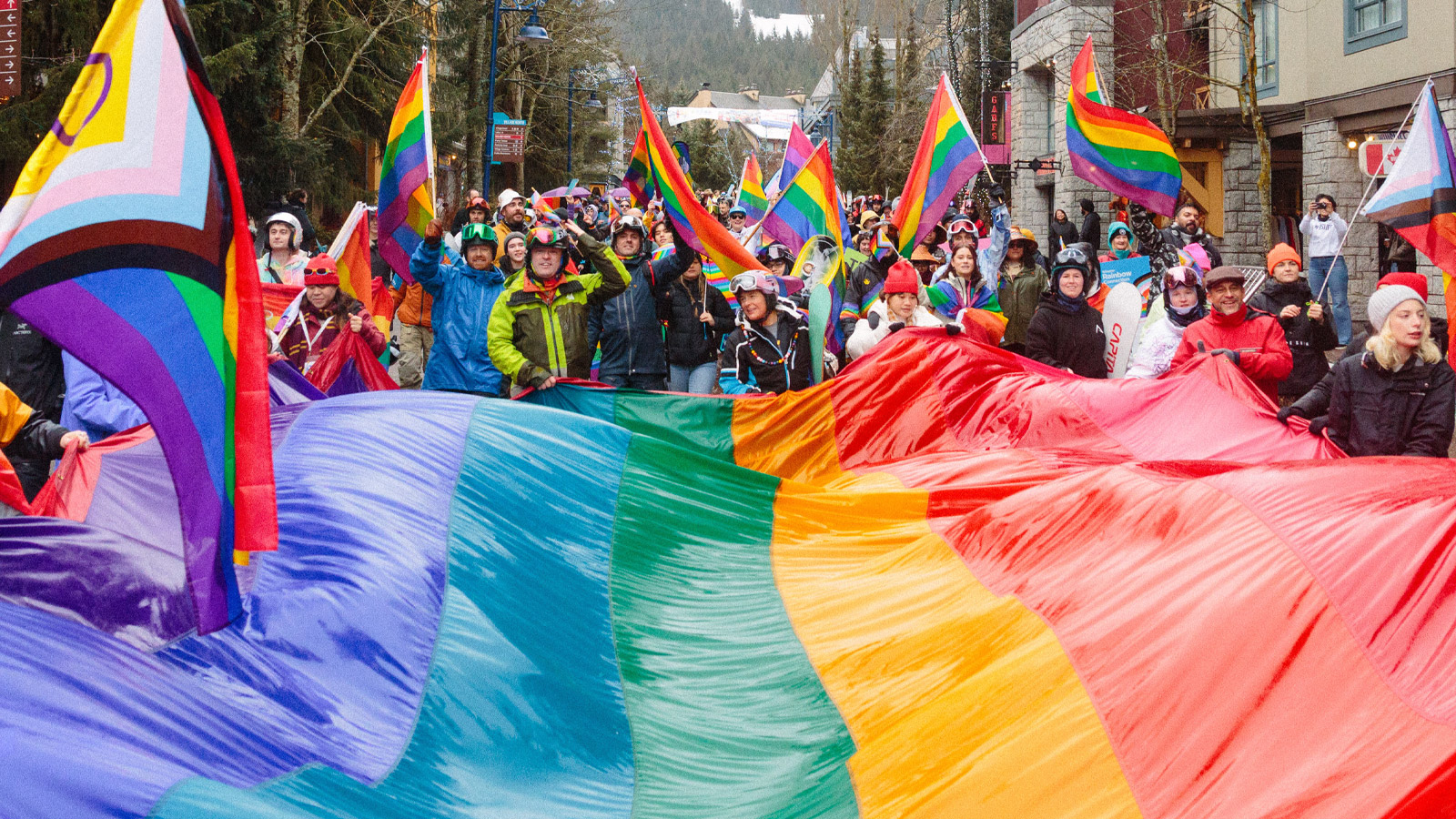 Whistler Pride Festival participants carrying a large rainbow flag through Whistler Village.