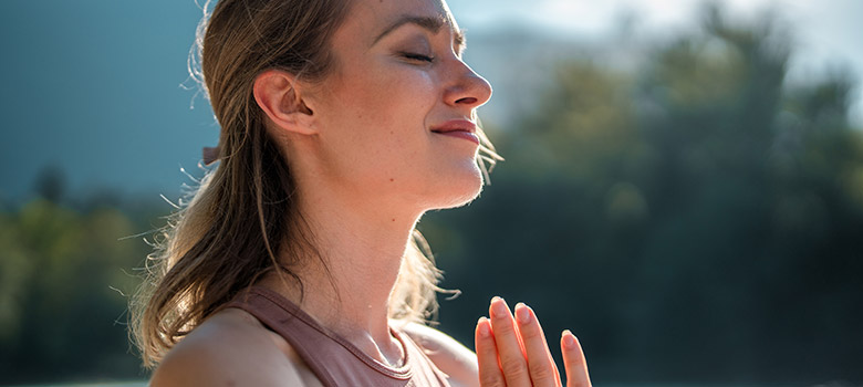 A closeup of a woman doing yoga with her face uptilted to the sunshine