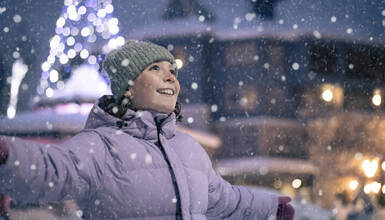 A person smiling and looking up at the falling snow in Whistler, British Columbia