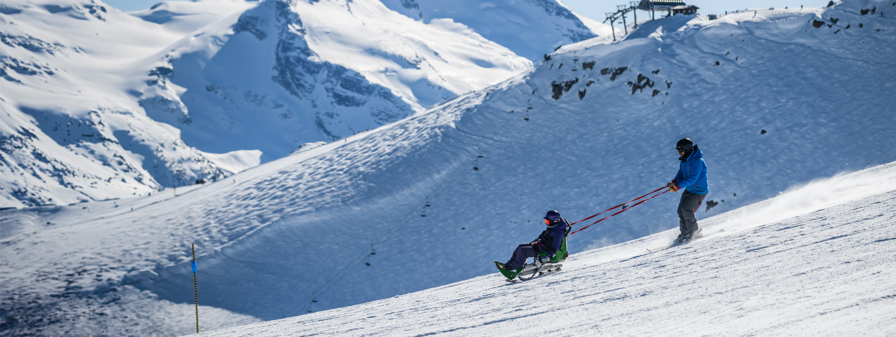 Whistler Adaptive assisting someone on a sit-ski