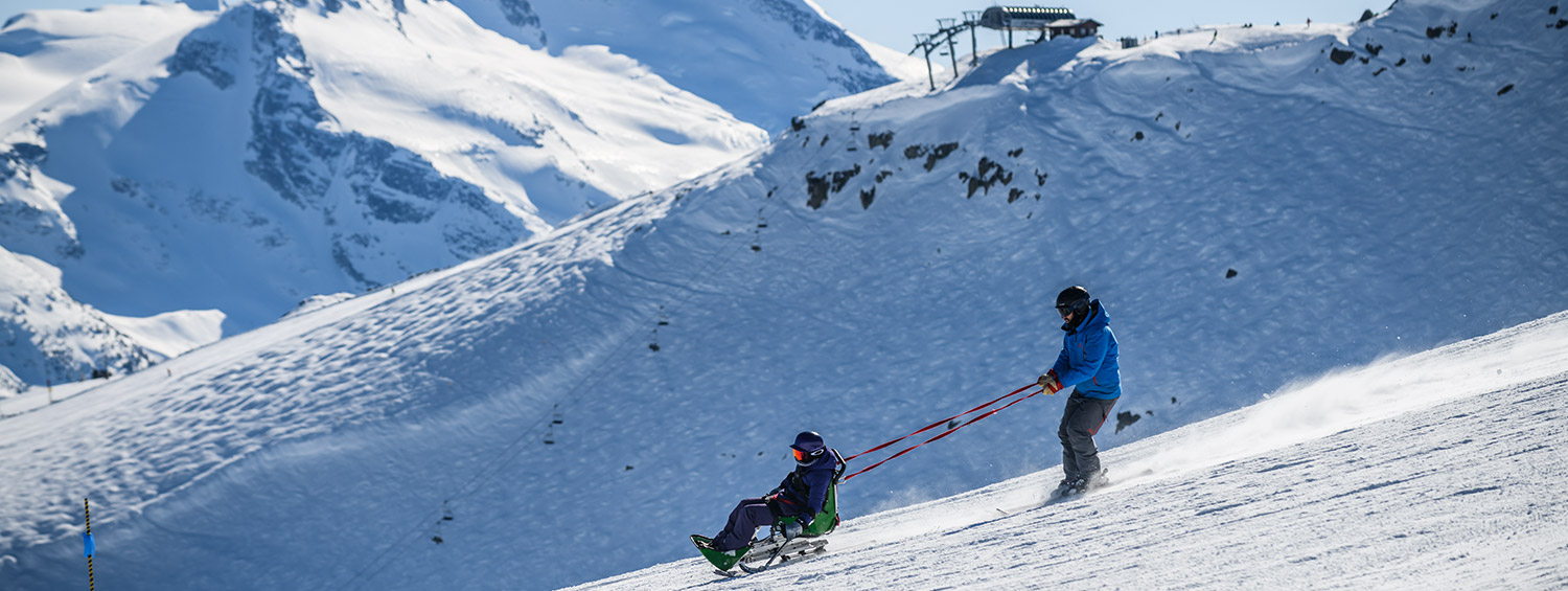 Whistler Adaptive assisting someone on a sit-ski