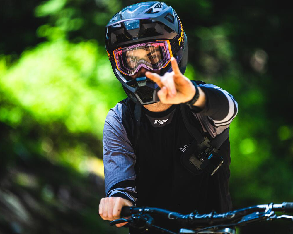 Mountain biker pauses on a forest trail, sharing local knowledge and riding tips in Whistler.