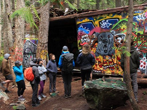 Visitors exploring the colourful abandoned boxcars at the historic Whistler Train Wreck.