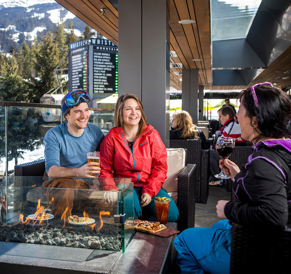 Three people enjoying spring apres on the patio at GLC