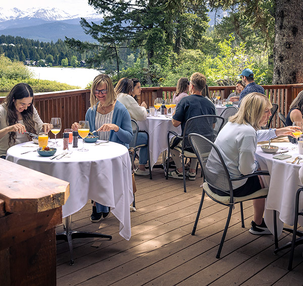 People enjoying dining outdoors at a lakeside Nourish Whistler Wellness Series event in spring