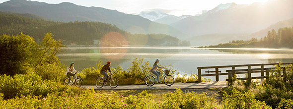 People riding cruiser bikes around Green Lake in Whistler in spring