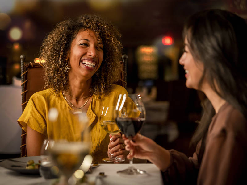 Two people dining and holding wine glasses at Bearfoot Bistro in Whistler Village