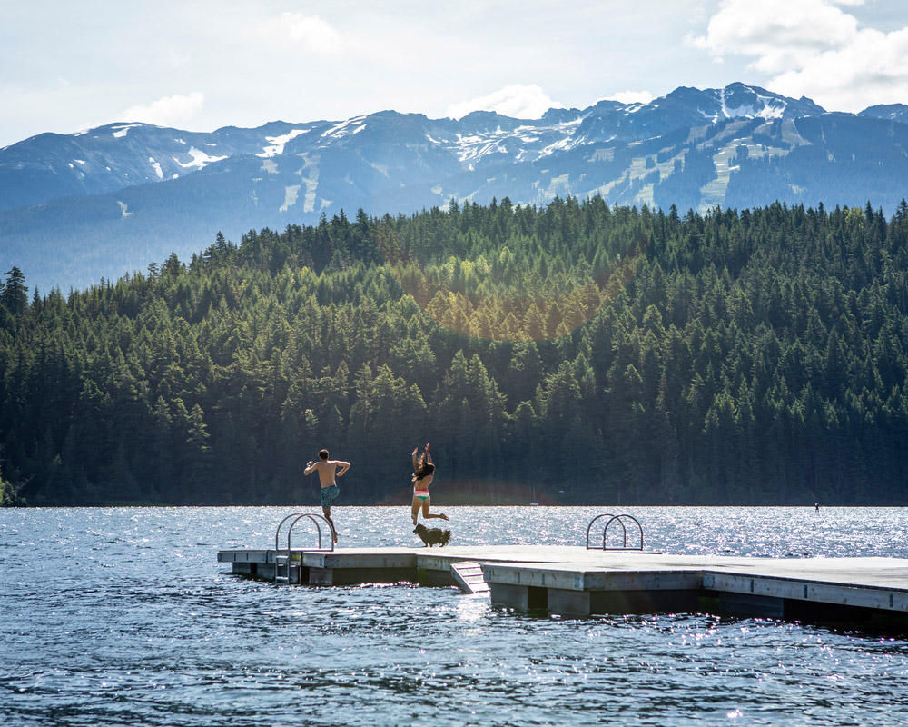 People jumping into the lake on a sunny Whistler day