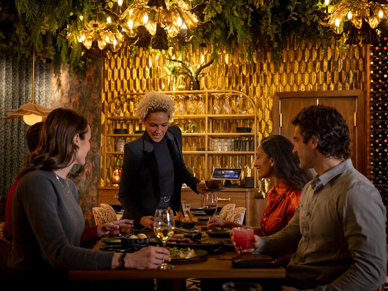 A server chatting with four people at a festive dining table in Whistler