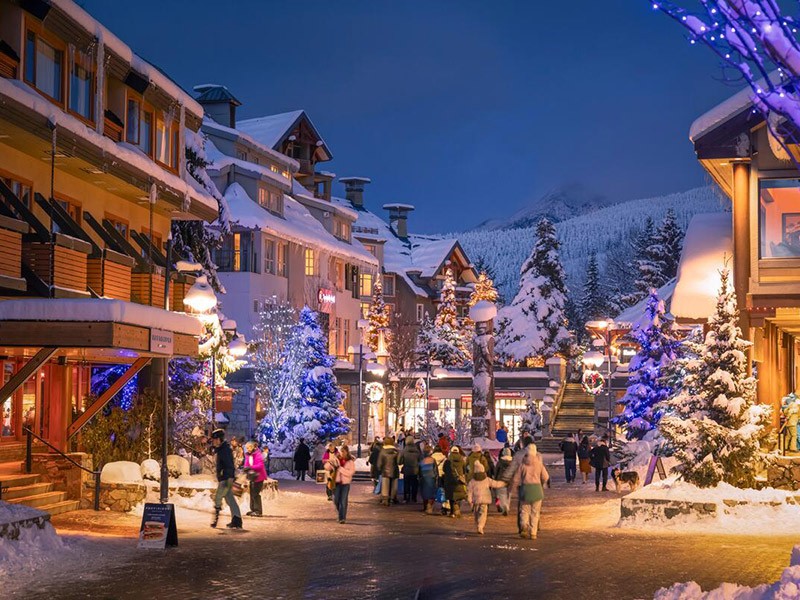 People walking along the stroll in Whistler Village, British Columbia on a snowy evening in winter.