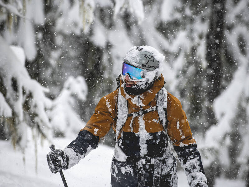 A skier covered in snow and smiling in Whistler