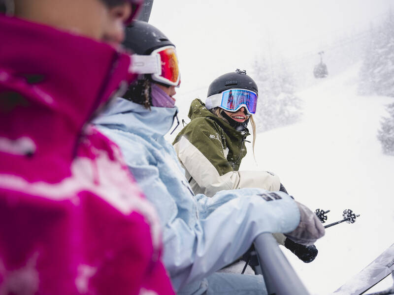 Group of three skiers smiling on Harmony Chairlift, Whistler Mountain