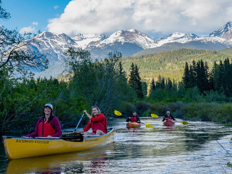 Guests canoeing through the River of Golden Dreams surrounded by lush vegetation in Whistler.