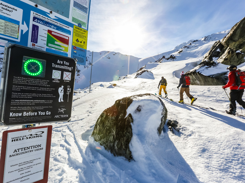 Backcountry skiers pass an avalanche transceiver checkpoint before entering the alpine terrain near Whistler Blackcomb, highlighting avalanche safety and backcountry travel preparation.