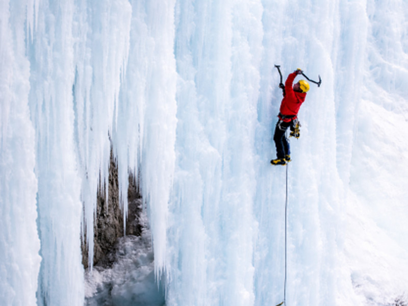 Ice climbing in Whistler, BC, climber using ice axes and crampons on a frozen waterfall with another climber above
