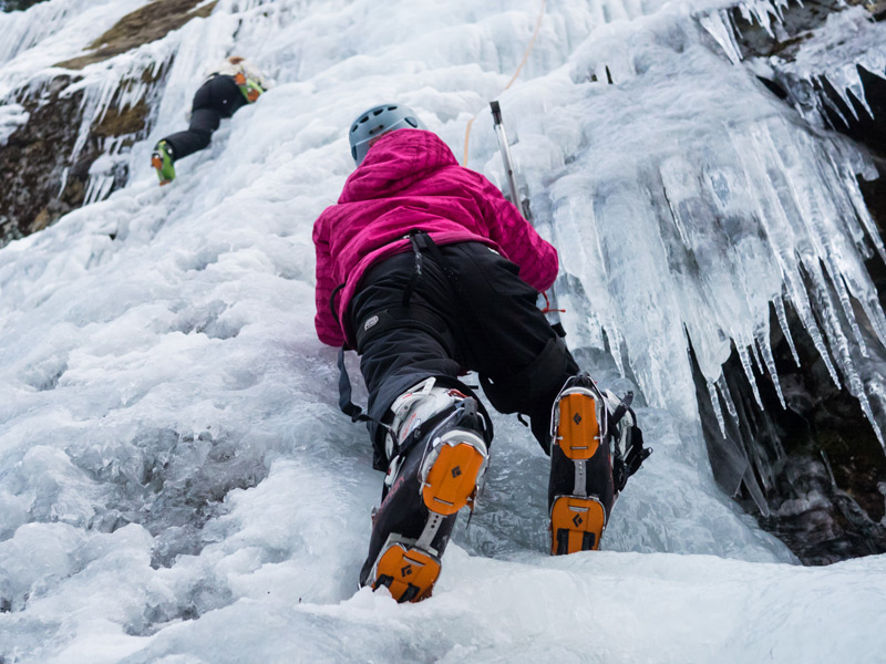 Ice climbing in Whistler, BC, climber using ice axes and crampons on a frozen waterfall with another climber above