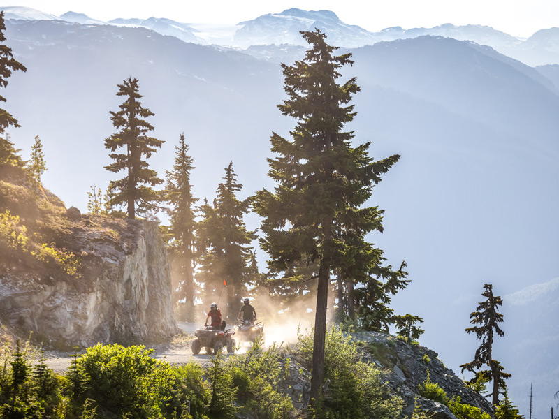Guests ride ATVs along a mountain trail on Blackcomb Mountain with panoramic views of Whistler Valley and the Coast Mountains.