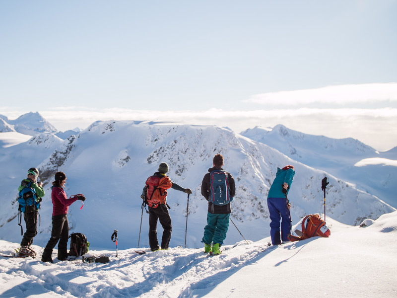 A certified ski guide introduces guests to backcountry skiing techniques while overlooking alpine terrain in Whistler's Coast Mountains.