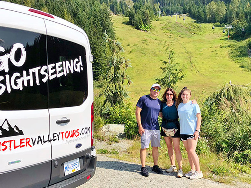 A private sightseeing vehicle overlooks Whistler Valley with panoramic mountain views, lakes and forests in the background.