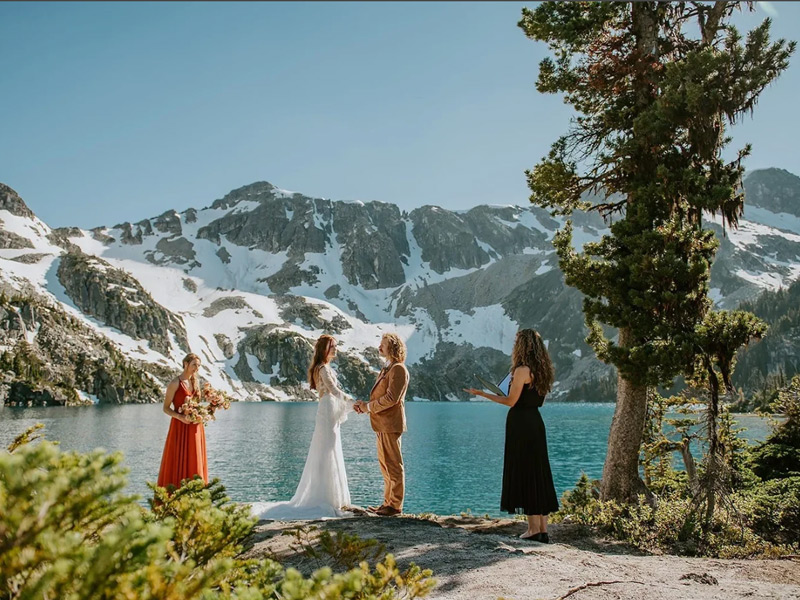 Bride and groom celebrating beside a helicopter in an alpine mountain setting near Whistler.