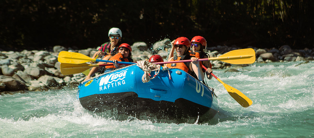 Friends feeling a rush as they raft down a river in Whistler