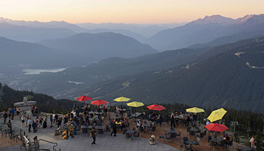 People dining on the patio at the Roundhouse Lodge at the top of Whistler Mountain in summertime
