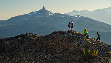 A group of hikers climb up a rocky alpine ridge on Whistler Mountain to get a view of Black Tusk across the valley.