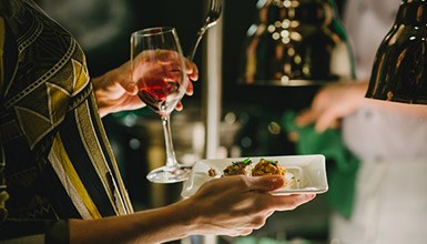 A person holding a glass of red wine and a plate of food at Cornucopia's Night Market event in Whistler Village